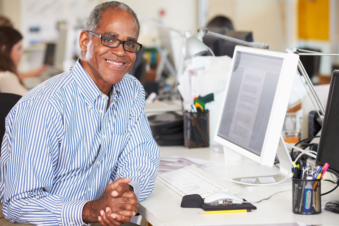 A elderly man sitting at his work desk